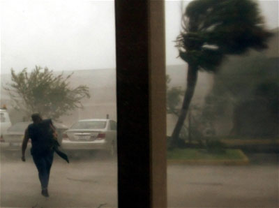 A man walks to his car as fights the winds of Hurricane Katrina