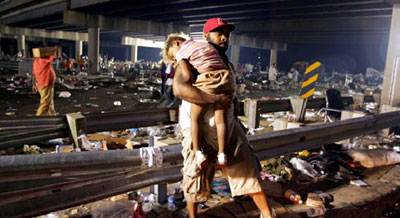 A man holds his exhausted daugheter as they await evacuation